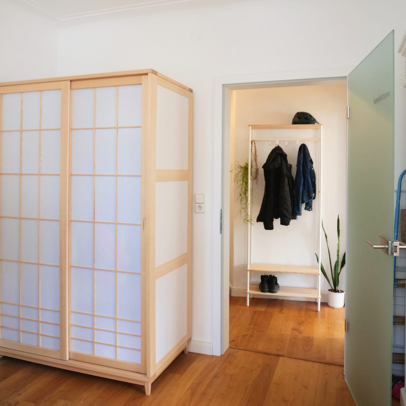 Kleiderschrank in Esche und Muji-Papier, dahinter Garderobe in Esche und weißem Stahl